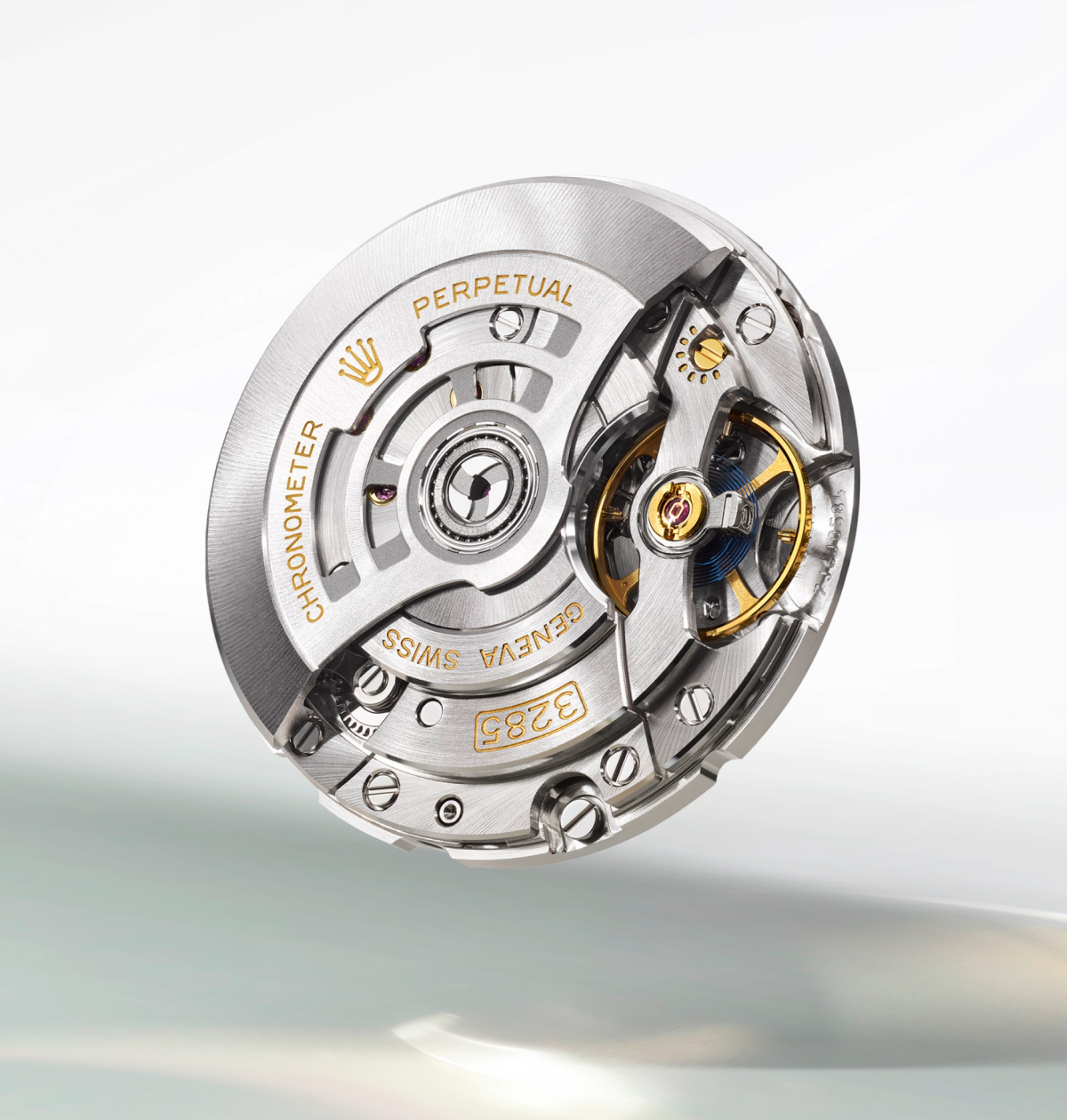 Close-up of a silver and gold mechanical watch movement labeled Swiss Chronometer 3285 with visible gears and intricate details on a light background.